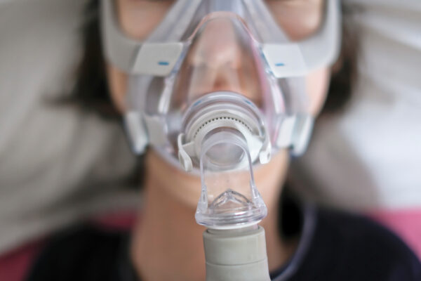 A woman sleeps in her bed with a cpap mask on her face